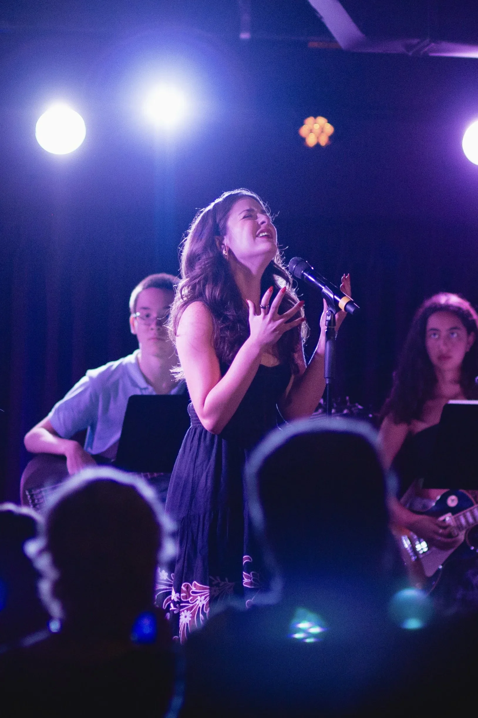 Emily singing passionately on stage under purple lighting