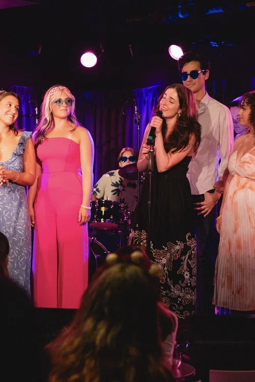 Group of young people performing on stage with bright lights